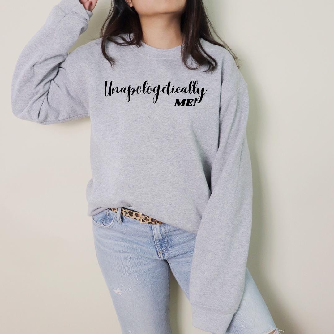 a woman wearing a grey sweatshirt with black lettering on it